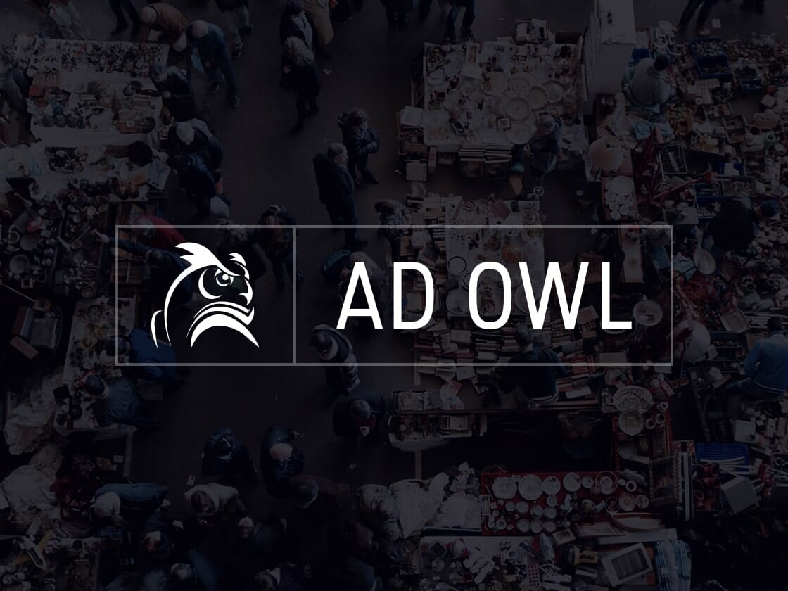 Portfolio-logo-AD-OWL A busy marketplace with numerous stalls and people seen from above. The scene is slightly blurred and overlaid with a transparent dark layer. At the center of the image, there's a logo of an owl's head and the text "AD OWL" displayed in white capital letters within a rectangular border.