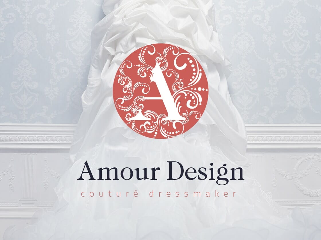 Portfolio-logo-amour-design A flowing white couture dress cascades down a light blue patterned wall with intricate white frame detailing. Overlaid in the center is a decorative red emblem featuring an ornate letter "A". Below this emblem, the text reads "Amour Design" with "couturé dressmaker" in smaller type beneath.