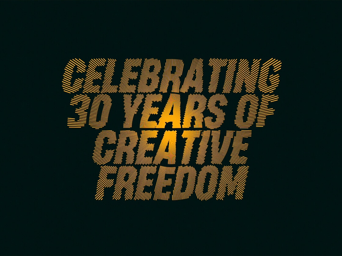 Basha Uhuru – 30 Years Of Creative Freedom looped video Celebrating 30 Years of Creative Freedom" is written in bold, yellow, diagonal striped text against a dark green background, with a glowing effect behind the words in a looped video that captures the essence of Basha Uhuru.